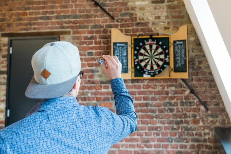 Familie und Freunde spielen gemeinsam Darts im Wohnzimmer als Freizeitspaß