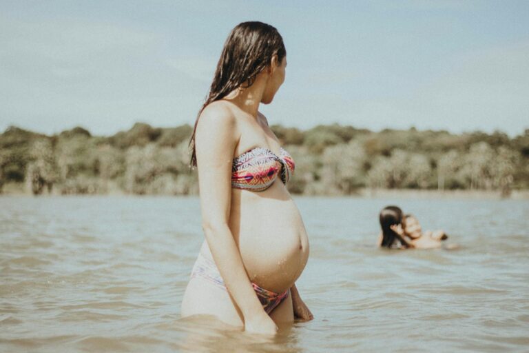Urlaub und Reisen in der Schwangerschaft erlaubt – so geht’s ohne Risiko Schwangere Frau entspannt mit Reisetasche am Meer im Urlaub unterwegs